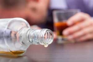 Bottle of alcohol and glass on table representing underage drinking and minor in possession cases near the University of Tennessee in Knoxville