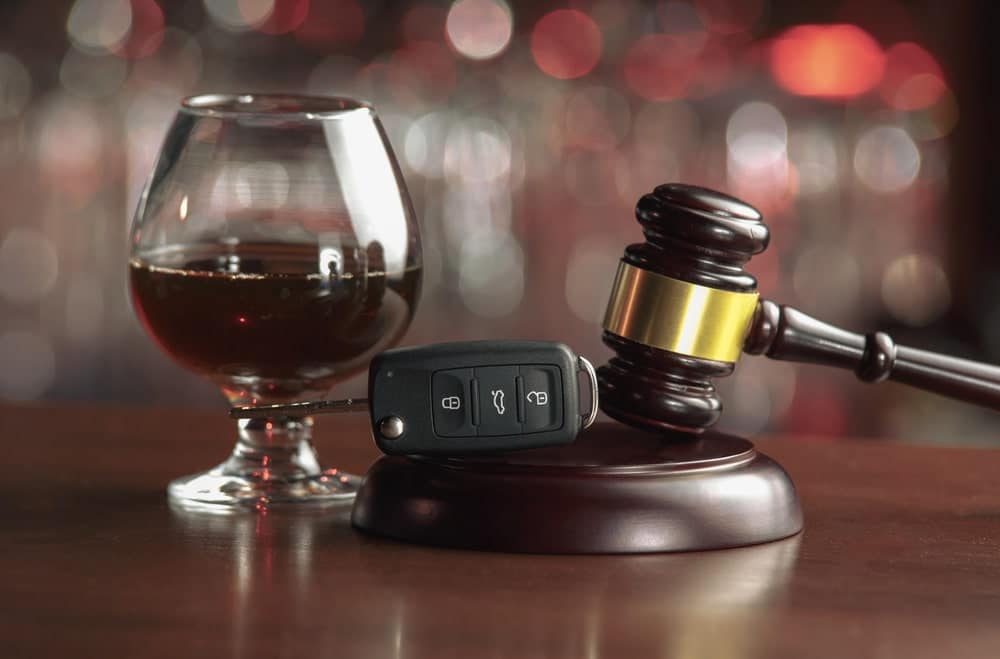 Image shows car keys beside a glass of alcohol and a judge’s gavel symbolizing DUI affects your education and legal consequences