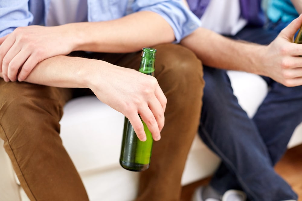 Image shows two young adults holding beer bottles, illustrating how campus drinking can lead to dui penalties for college students.